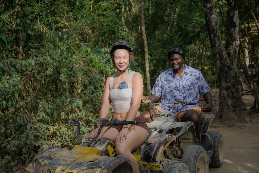 Couple riding quads through jungle trails on a Tulum ATV tour