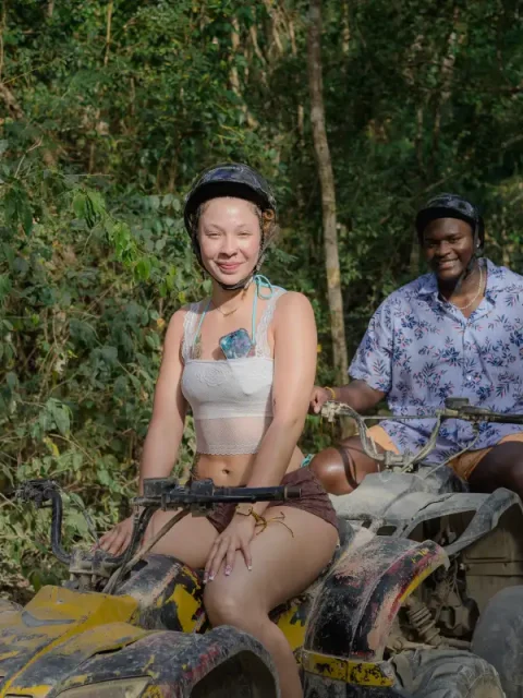 Couple riding quads through jungle trails on a Tulum ATV tour