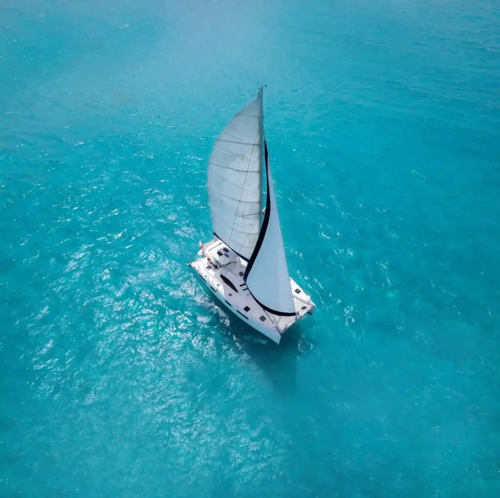 Top-down aerial of a catamaran sailing on an isla mujeres catamaran tour through turquoise waters