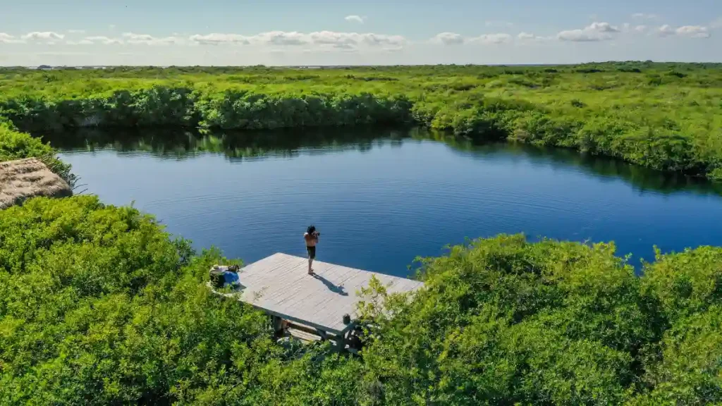 Visitor on wooden platform overlooking Cenote Cormoran lagoon in Tulum