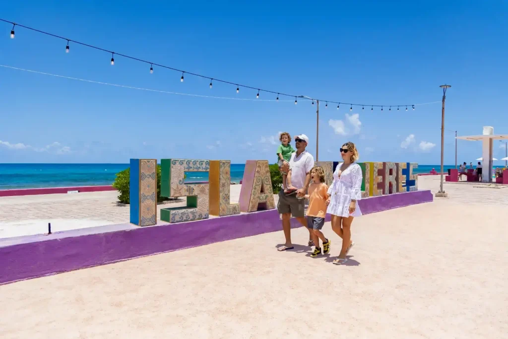 Family posing in front of the colorful Isla Mujeres sign on the waterfront boardwalk