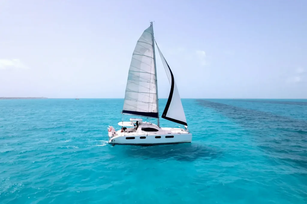 White sailing catamaran with full sails on calm turquoise Caribbean water