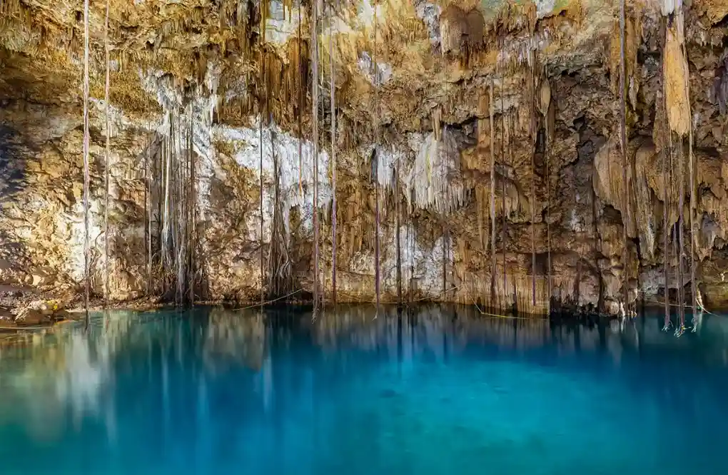 Stunning cave cenote in Yucatan, Mexico with clear turquoise water.