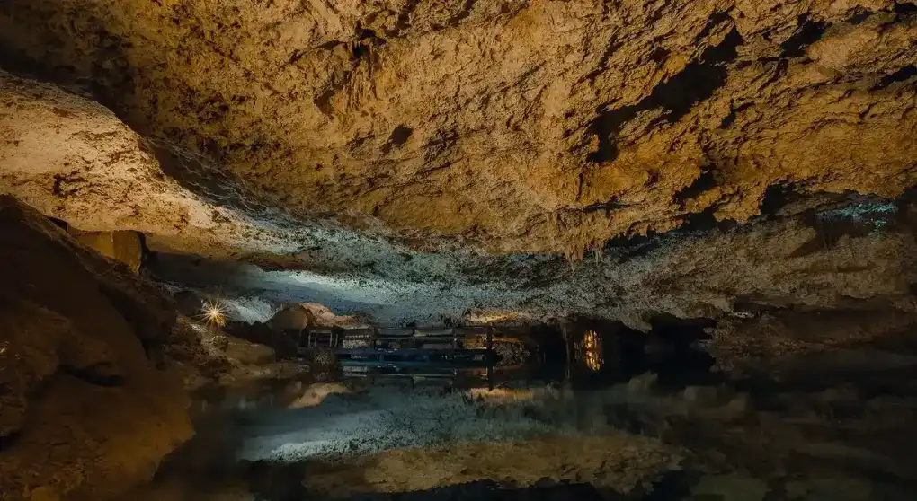 Underground cenote with lighting and seating for tourists during private tours.
