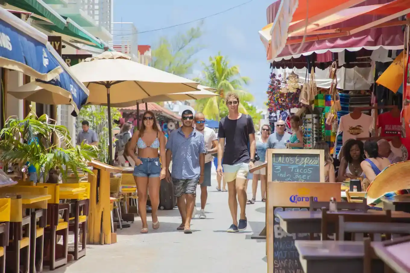 Tourists walking through a lively outdoor market street in downtown Isla Mujeres