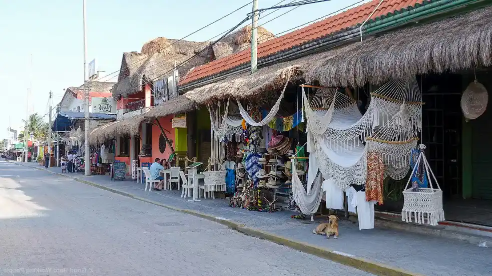 Local shops and hammocks along a colorful street in Tulum Pueblo.