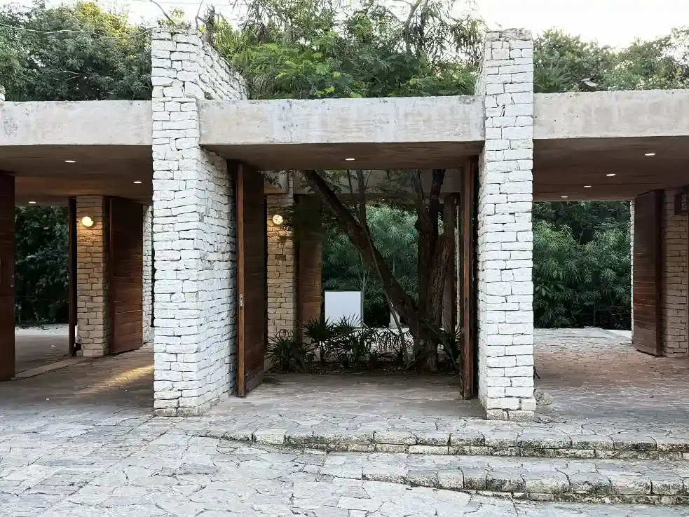 Modern stone and wood entrance structure at the Tulum Ruins box office, surrounded by lush greenery and natural elements.